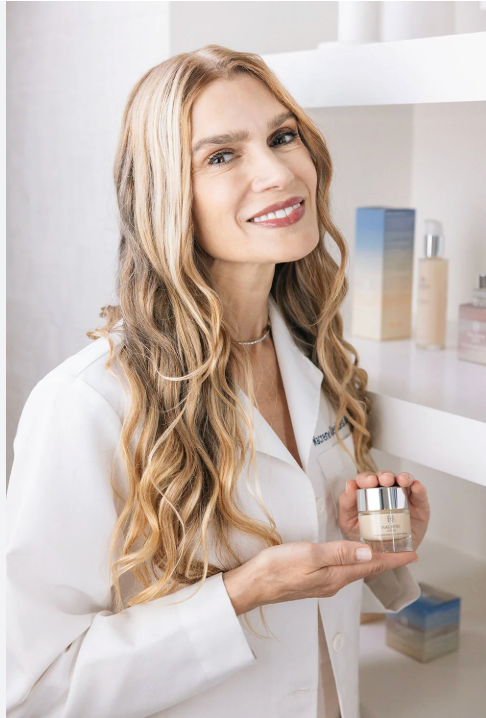 Woman in a white coat holding a skincare product in a clinical setting